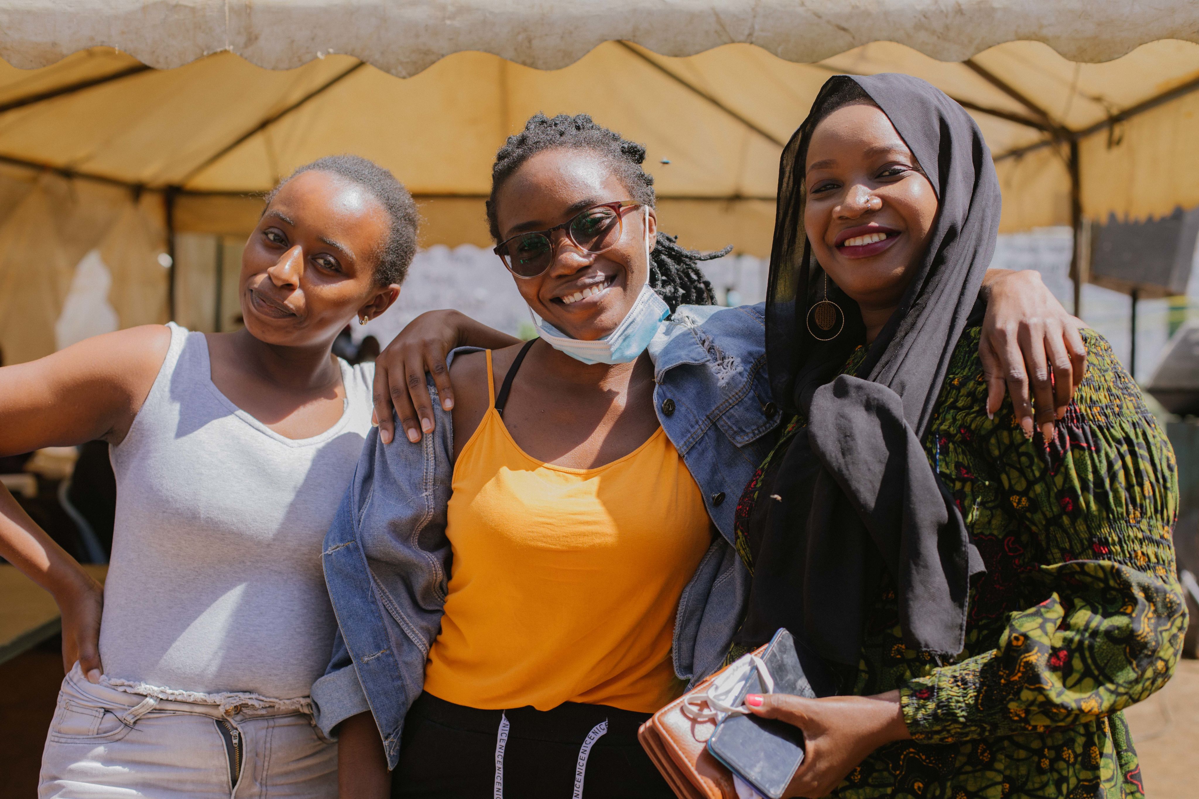 Three community members hugging and smiling.